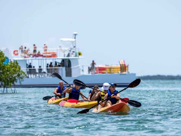people kayaking with a boat in the background